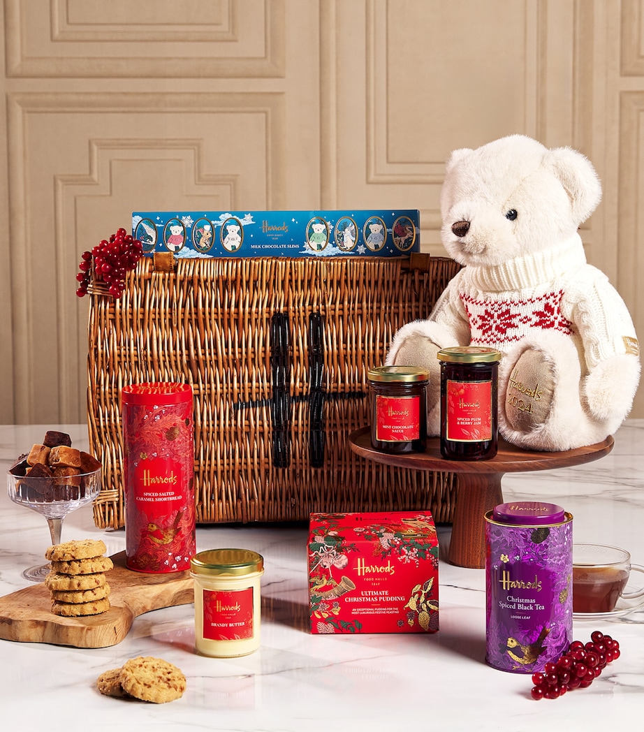 An open Harrods The Grosvenor Christmas hamper featuring sweet preserves, teas, chocolate, candles, and a teddy bear in a jumper