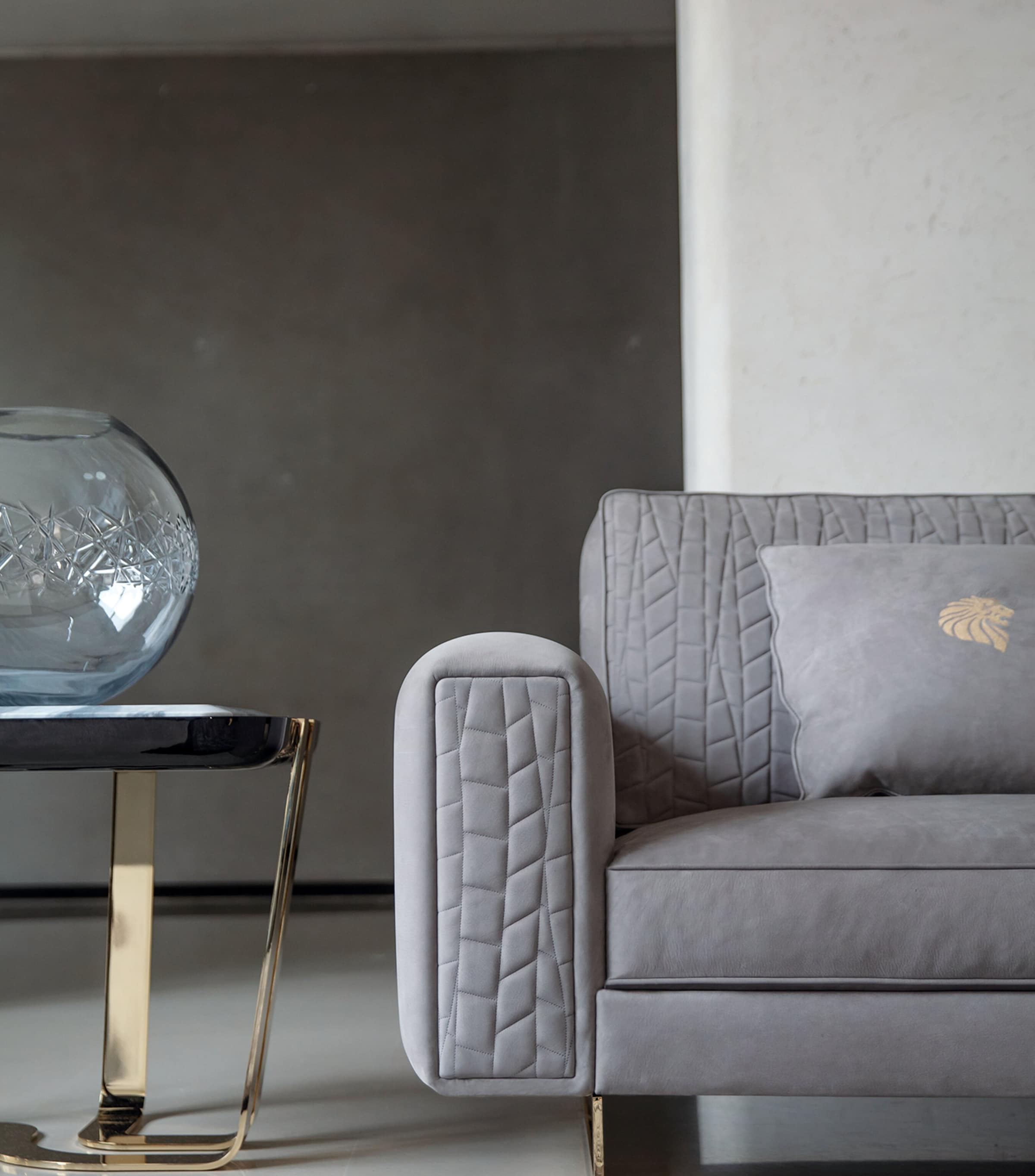 Close-up of sofa arm with quilted pattern and grey cushion