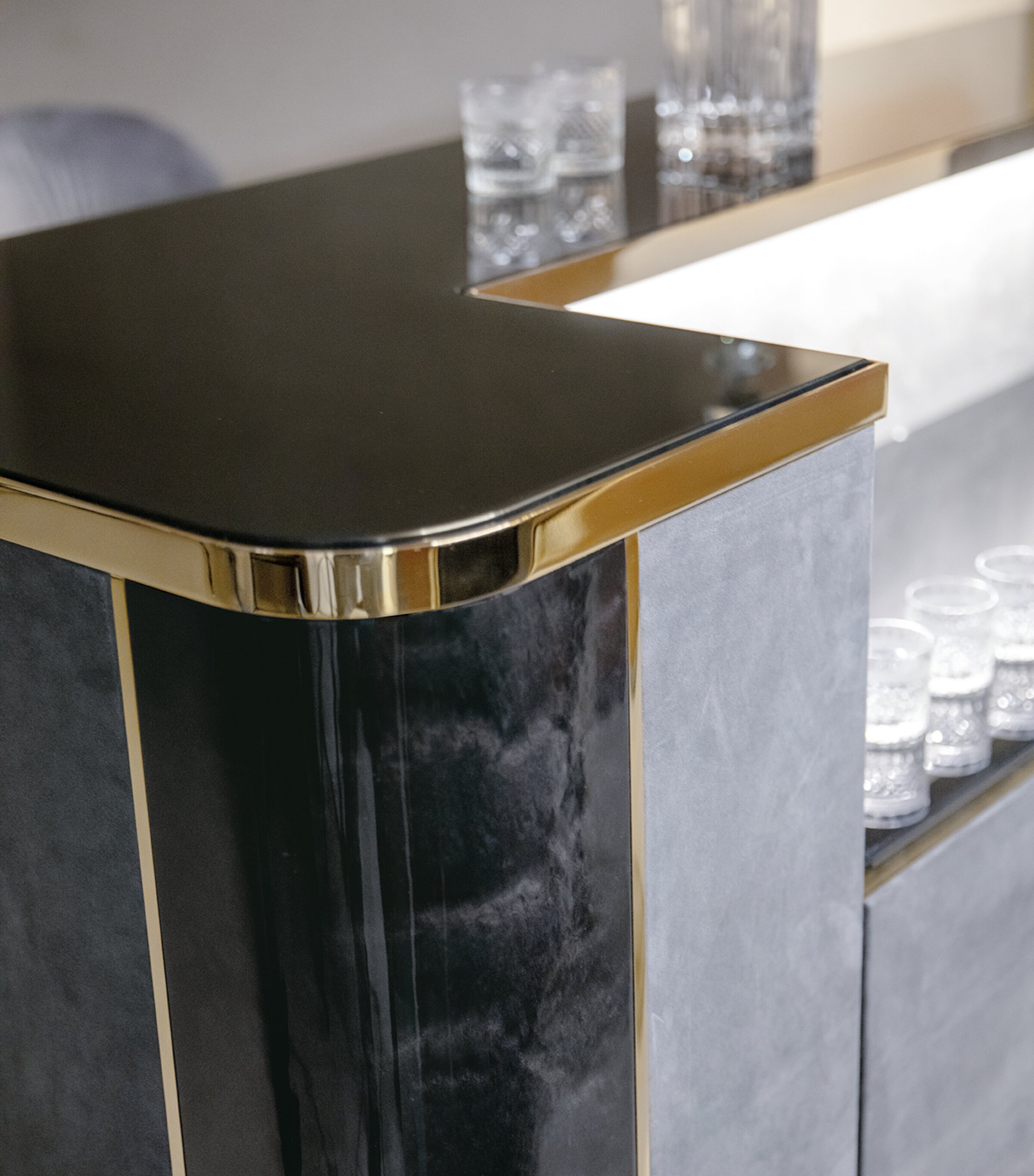 Corner detail of Charisma bar with black countertop and gold trim